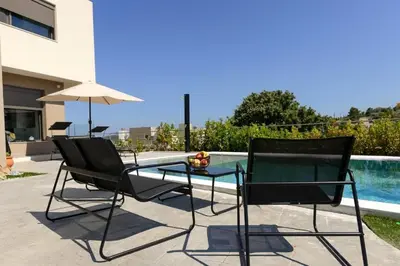 two chairs and a glass table next to a pool at Aetheria Luxury Villa in Kalithies