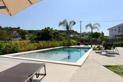 a swimming pool with chairs and a table and an umbrella at Aetheria Luxury Villa in Kalithies