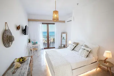 a white bedroom with a bed and a table at Marieta Suite in Vrachonisída touArchangélou