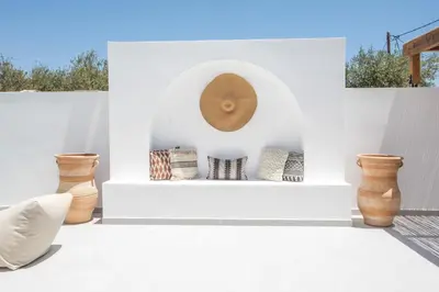a white patio with vases and a clock on a wall at Zaia Suites & Living, Suite N3, pool view, central in Gennadi