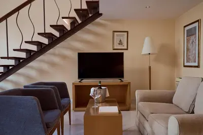 a living room with a tv and a staircase at Lindian Dream Seaside Resort- Adults Only in Líndos