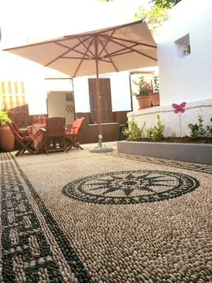 a tiled patio with an umbrella and a table and chairs at Villa Elena in Líndos
