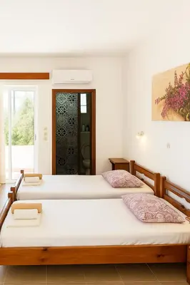 two beds in a room with white walls at Merryland Studios & Apartments in Kremasti