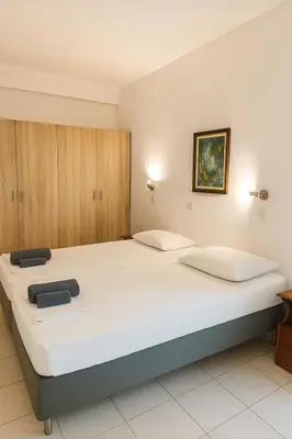 a bedroom with two beds and wooden cabinets at Merryland Studios & Apartments in Kremasti