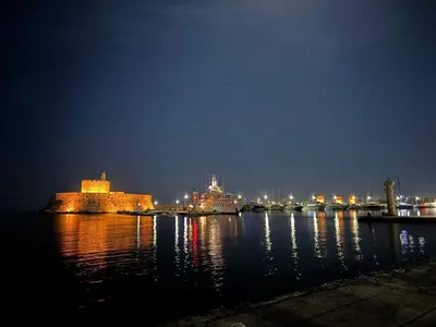 a castle sitting on the water at night at V&G Cozy Home, Pilona Village in vlicha