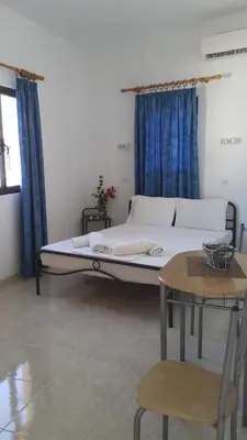 a bed in a room with blue curtains and a table at Lindos Center Studios in Líndos