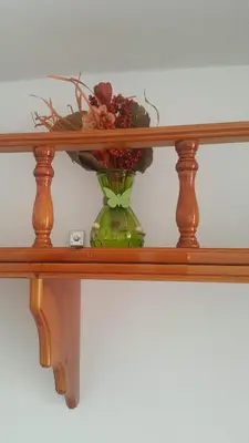 a green vase with flowers on a wooden shelf at Lindos Center Studios in Líndos