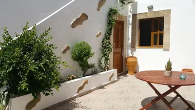 a patio with a table and plants on the wall at Lindos Center Studios in Líndos