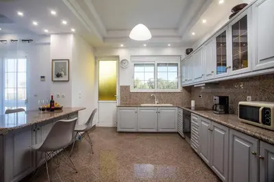 a large kitchen with white cabinets and a sink at Malibu Villa in Kremasti