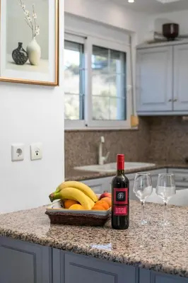 a bottle of wine sitting next to two wine glasses at Malibu Villa in Kremasti