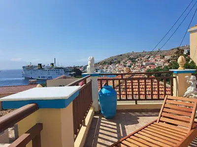 a balcony with two chairs and a cruise ship at Villa Efraim Amalia in Halki
