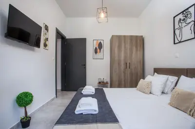 a bedroom with a large white bed with a flat screen tv at Ixia del Mar Apartment in Ixia