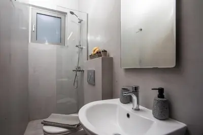 a white bathroom with a sink and a shower at Ixia del Mar Apartment in Ixia