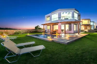 a house with a pool and two lawn chairs at Aqua Natura Villas in Lachania