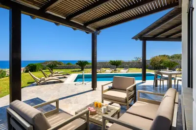 a patio with chairs and a table and a pool at Aqua Natura Villas in Lachania