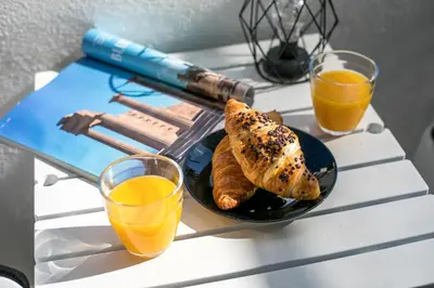 a table with a plate of food and two glasses of orange juice at Ixia del sol Apartment in Ixia