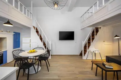 a living room with a table and chairs and stairs at Lemonitissa Villa in Symi