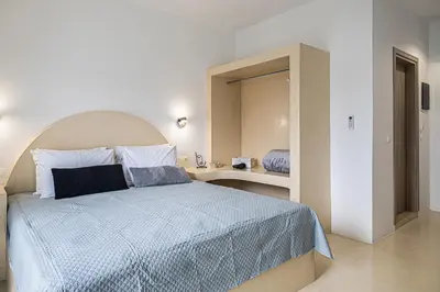 a bedroom with a bed with a blue comforter and a mirror at Gaia Rooms in Vrachonisída touArchangélou
