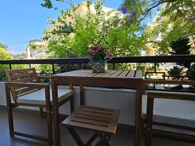 a wooden table and chairs on a balcony with a vase of flowers at S & E luxury city residences in Rhodes Town