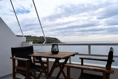 a table and chairs on a balcony with a view of the ocean at Eraya Apartment in Haraki