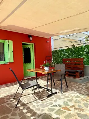 a table and chairs in front of a red wall at Marine's apartments in Symi