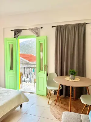a bedroom with green doors and a table with chairs at Marine's apartments in Symi