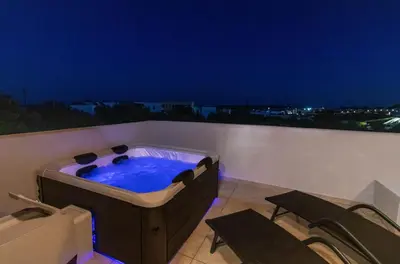 a hot tub on a balcony with two chairs at Kolymbia Bella View House in Kolimbia