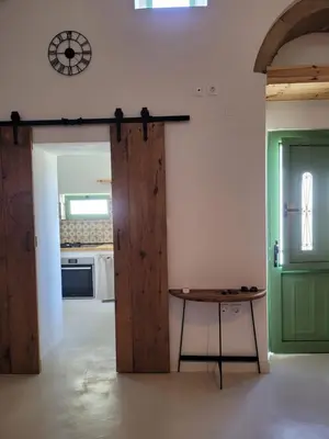a kitchen with a table and a clock on the wall at Makariospiti - Villa Vera in Malona Village