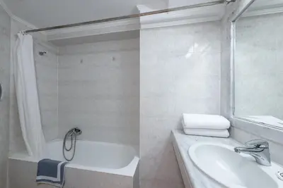 a white bathroom with a tub and a sink at Sirene Beach Hotel in Ixia