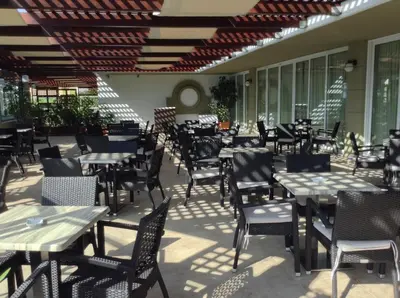 an empty restaurant with tables and chairs on a patio at Sirene Beach Hotel in Ixia