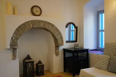 a room with an arch with a clock on the wall at Caza Rina Appartment, Symi in Symi