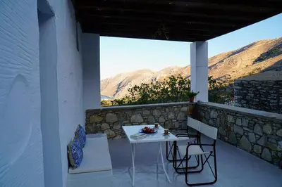 a white table and chairs on a balcony with mountains at Caza Rina Appartment, Symi in Symi