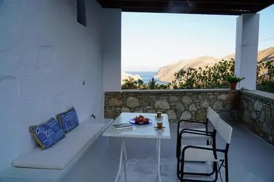 a table and chairs on a balcony with a view of the ocean at Caza Rina Appartment, Symi in Symi