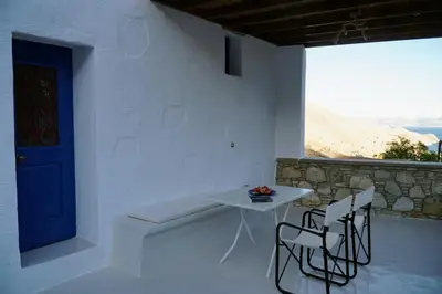 a white room with a table and chairs and a blue door at Caza Rina Appartment, Symi in Symi