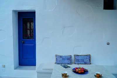 a table with a bowl of fruit and a blue door at Caza Rina Appartment, Symi in Symi