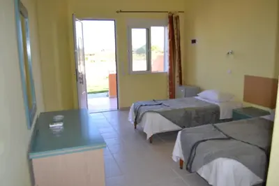 a hotel room with two beds and a table at To Akrogiali in Phanaes