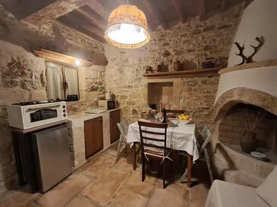 a kitchen with a table and a stove top oven at Thelya - Stone House in Apóllona