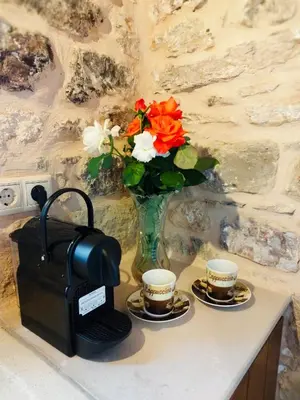 a table with two cups of coffee and a vase with flowers at Thelya - Stone House in Apóllona