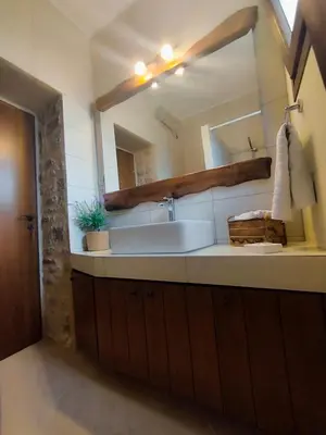 a bathroom with a sink and a large mirror at Thelya - Stone House in Apóllona