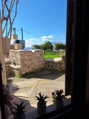 a view of a patio from a window with potted plants at Thelya - Stone House in Apóllona