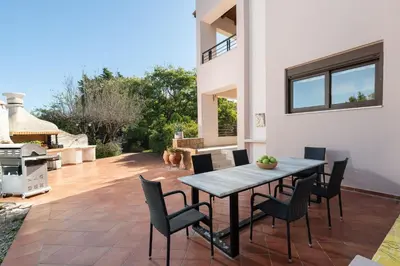 a patio with a table and chairs and a grill at Coral Tree Luxury Villa in Ialyssos