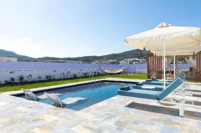 a swimming pool with two chairs and an umbrella at Ελin Villa in Kalathos