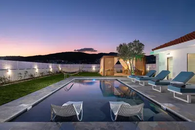 a swimming pool with chairs and a house at Ελin Villa in Kalathos