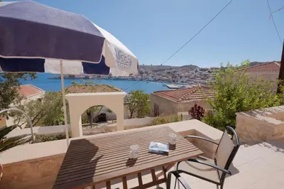 a wooden table and chairs with an umbrella on a patio at Harbour View Modern Apartments with Terrace in Halki
