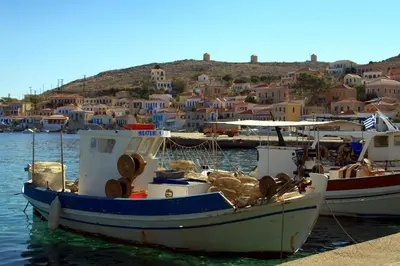 two boats are docked in a harbor with houses at Harbour View Modern Apartments with Terrace in Halki