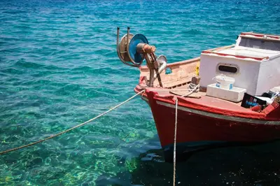 a red boat is tied to the water at Harbour View Modern Apartments with Terrace in Halki