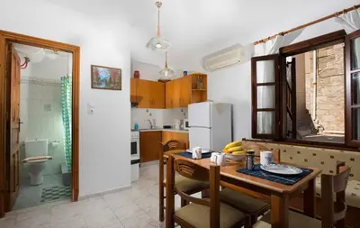 a kitchen with a table and a kitchen with a refrigerator at Charming Waterfront Studio with swimming access in Halki