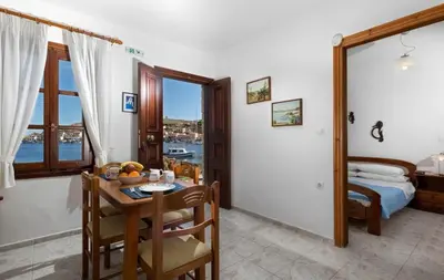 a dining room with a table and a bedroom at Charming Waterfront Studio with swimming access in Halki