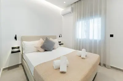 a white bedroom with a bed with towels on it at Alter Ego Cozy Corner in Rhodes Town