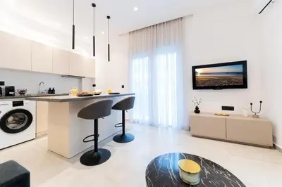 a kitchen with white cabinets and a counter with a table at Alter Ego Cozy Corner in Rhodes Town